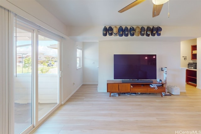 living room featuring a wealth of natural light, light wood-type flooring, and ceiling fan