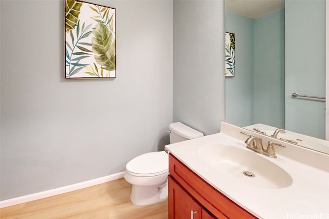 bathroom with toilet, hardwood / wood-style floors, and vanity