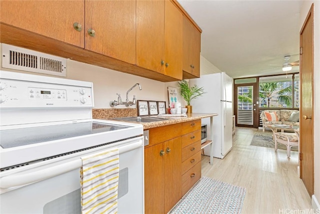 kitchen with white appliances, light hardwood / wood-style floors, ceiling fan, and sink