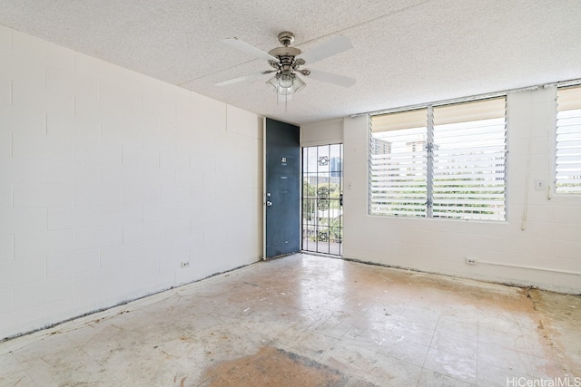 unfurnished room with ceiling fan and a textured ceiling