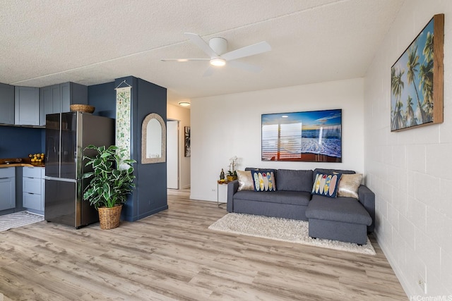 24 Hialoa St Unit 41, Honolulu, HI 96817 - living area with concrete block wall, a textured ceiling, ceiling fan, and light wood-style flooring
