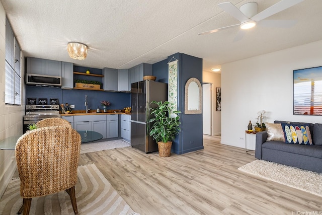 24 Hialoa St Unit 41, Honolulu, HI 96817 - kitchen featuring appliances with stainless steel finishes, light wood-style flooring, open shelves, open floor plan, and a textured ceiling