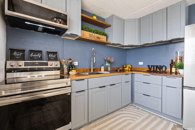 24 Hialoa St Unit 41, Honolulu, HI 96817 - kitchen with stainless steel electric range oven, open shelves, a sink, and butcher block counters