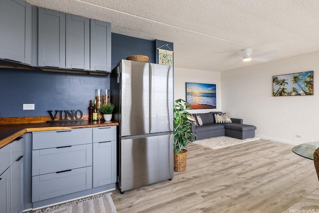 24 Hialoa St Unit 41, Honolulu, HI 96817 - kitchen featuring concrete block wall, a textured ceiling, butcher block countertops, freestanding refrigerator, and light wood-type flooring