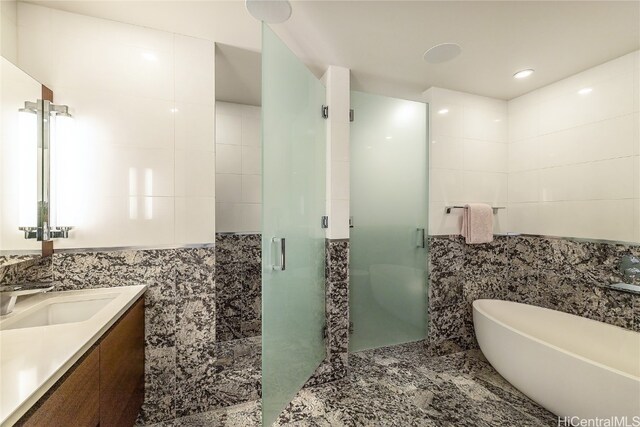 bathroom with tile walls, separate shower and tub, and vanity