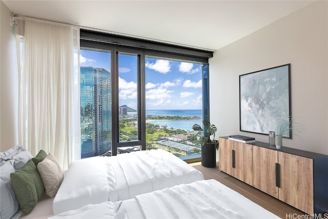 bedroom with light hardwood / wood-style flooring, a water view, and floor to ceiling windows