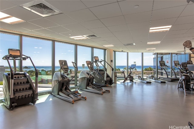 gym with a wall of windows, a water view, and a healthy amount of sunlight