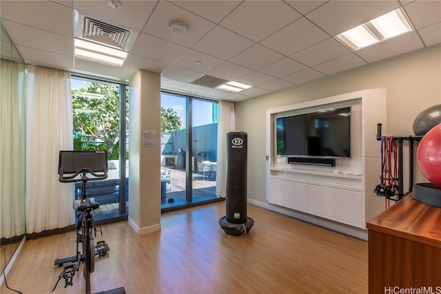 exercise room featuring light hardwood / wood-style floors and a paneled ceiling