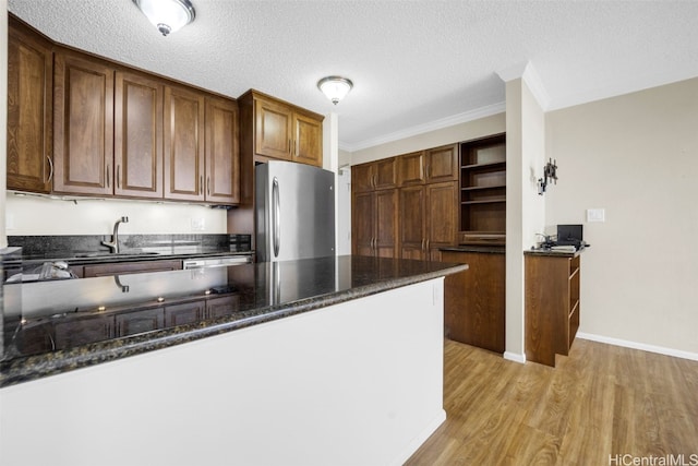 kitchen featuring stainless steel fridge, a textured ceiling, light hardwood / wood-style flooring, ornamental molding, and sink