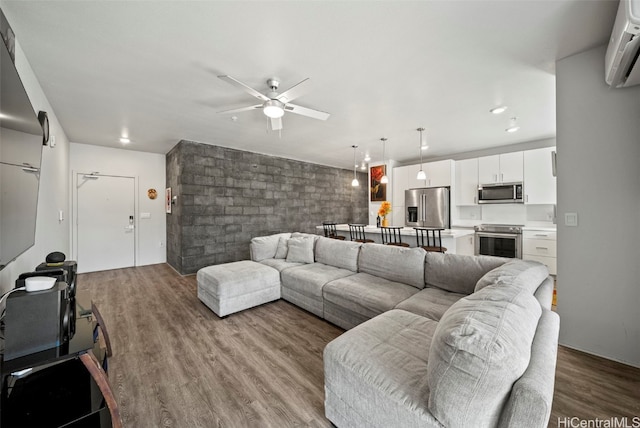 living room with an AC wall unit, light hardwood / wood-style flooring, and ceiling fan