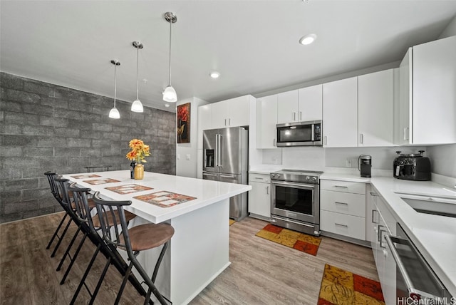 kitchen with sink, a breakfast bar, white cabinetry, appliances with stainless steel finishes, and light hardwood / wood-style floors