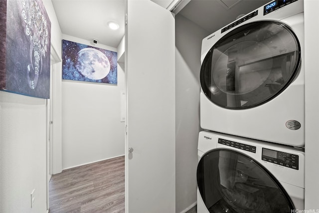 laundry room featuring stacked washer / dryer, wood finished floors, and laundry area