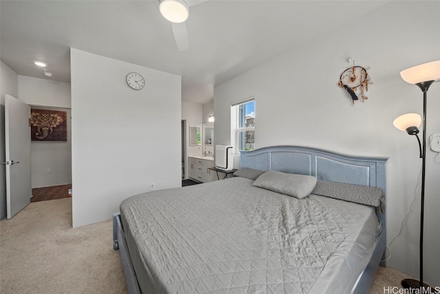 bedroom featuring ensuite bath, light colored carpet, and ceiling fan