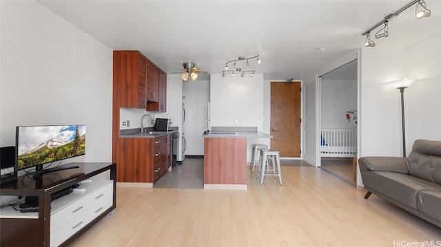 kitchen with ceiling fan, a kitchen breakfast bar, radiator, light hardwood / wood-style flooring, and a center island