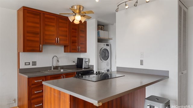 kitchen featuring sink, black electric cooktop, kitchen peninsula, ceiling fan, and stacked washer and dryer