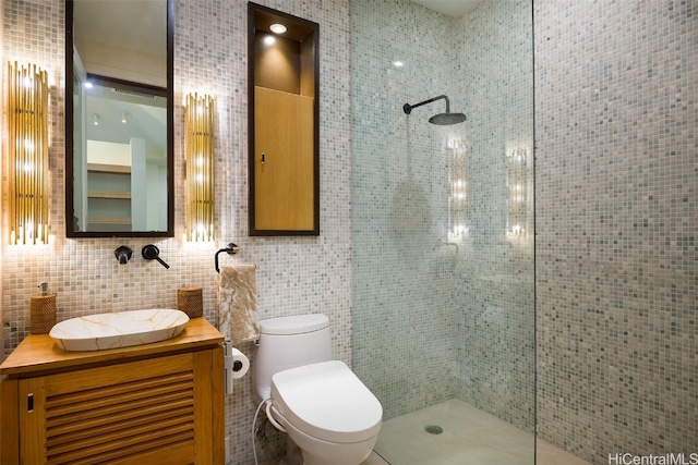 bathroom featuring tasteful backsplash, tile walls, toilet, tiled shower, and vanity