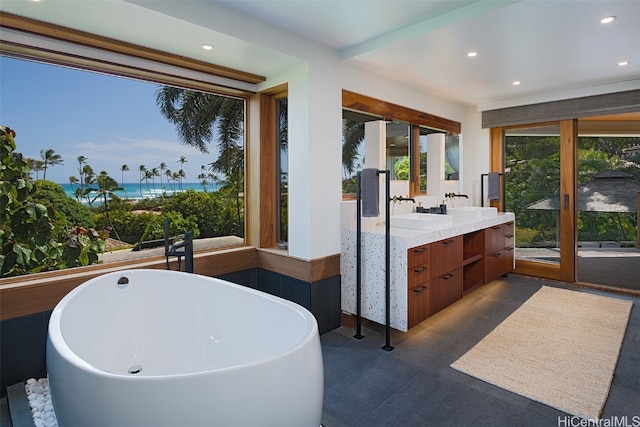 bathroom with vanity, a water view, and a bath