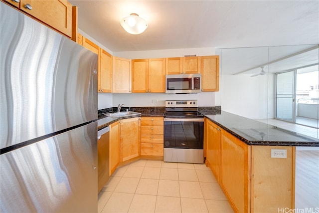 kitchen featuring kitchen peninsula, sink, dark stone countertops, and appliances with stainless steel finishes