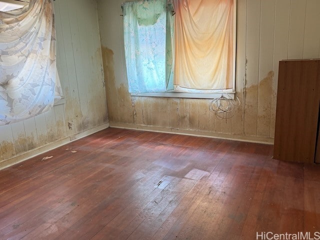 empty room with wood walls and dark hardwood / wood-style floors