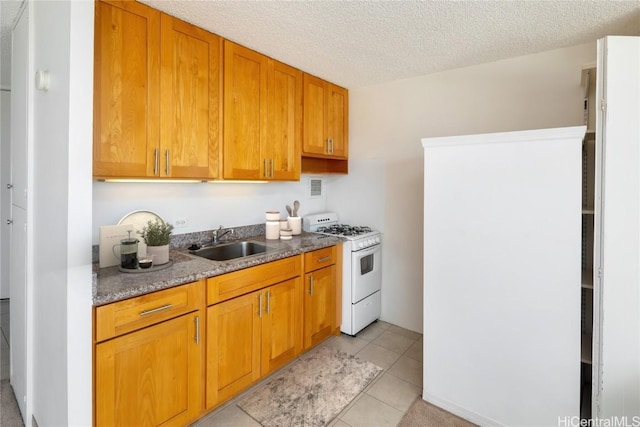 kitchen featuring sink, white gas range oven, a textured ceiling, and light tile patterned floors