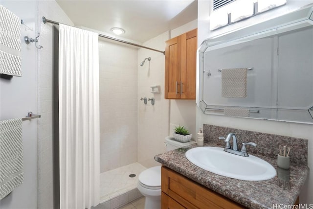 bathroom with vanity, toilet, and tiled shower