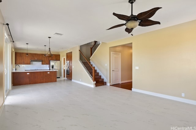 unfurnished living room featuring ceiling fan and sink