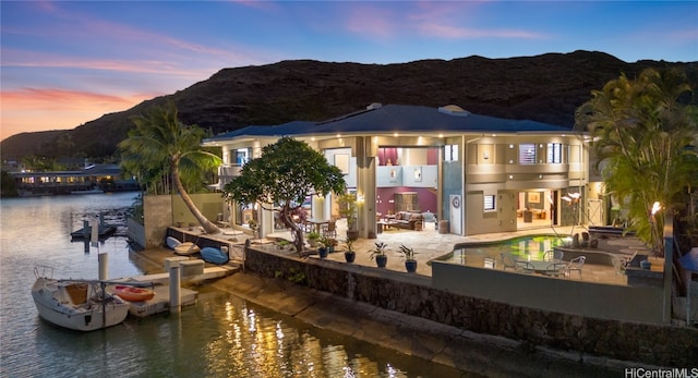 back house at dusk with a water and mountain view and a patio