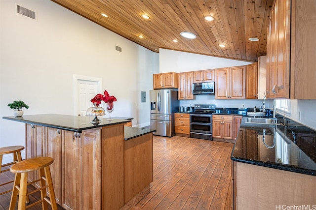 kitchen featuring wood ceiling, a breakfast bar, hardwood / wood-style flooring, sink, and stainless steel appliances