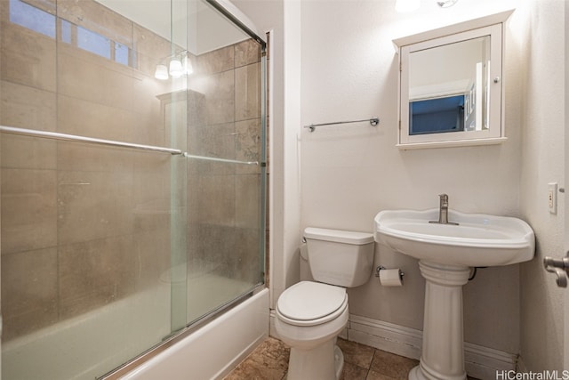 bathroom with toilet, tile patterned flooring, and bath / shower combo with glass door