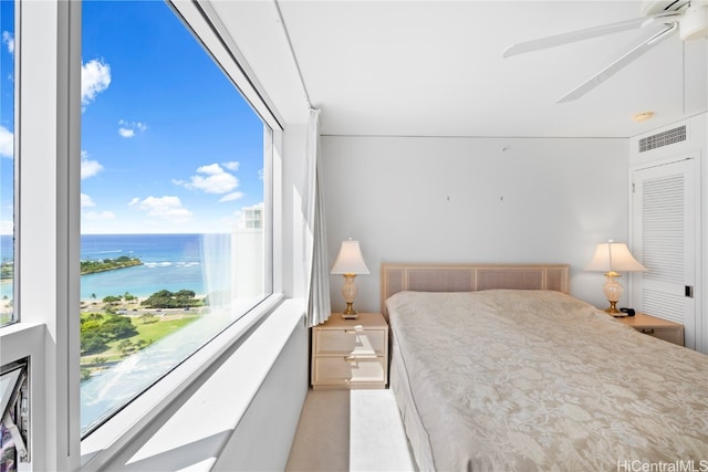 carpeted bedroom featuring multiple windows, a water view, and ceiling fan