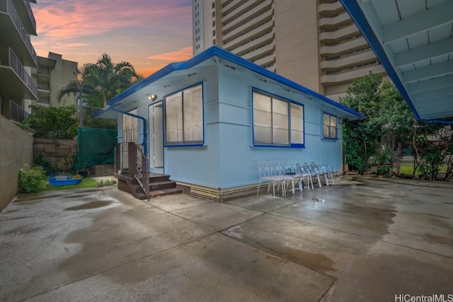 property exterior at dusk featuring a patio area