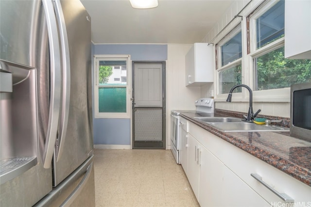 kitchen featuring sink, appliances with stainless steel finishes, white cabinets, and dark stone counters