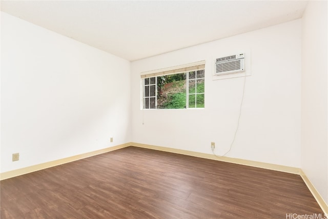 spare room featuring a wall mounted AC and dark hardwood / wood-style floors