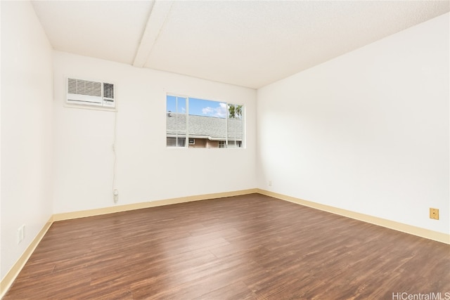 spare room featuring dark hardwood / wood-style flooring and a wall mounted air conditioner