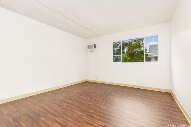 spare room with a textured ceiling, a wall mounted air conditioner, and dark hardwood / wood-style flooring