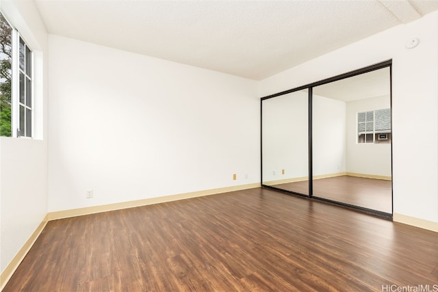 unfurnished bedroom featuring a textured ceiling, a closet, and dark hardwood / wood-style flooring