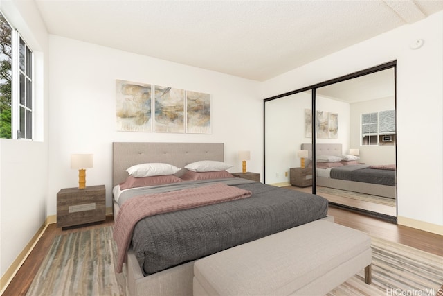 bedroom with a closet, wood-type flooring, and a textured ceiling