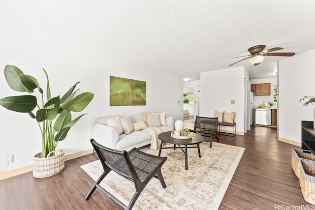 living area with a ceiling fan, baseboards, dark wood finished floors, and a textured ceiling