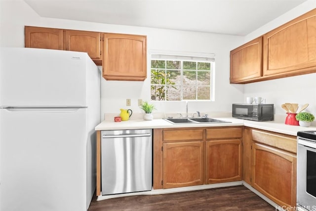 kitchen with black microwave, a sink, light countertops, stainless steel dishwasher, and freestanding refrigerator