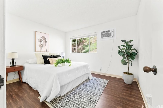 bedroom with dark wood-style flooring, a wall mounted air conditioner, and baseboards