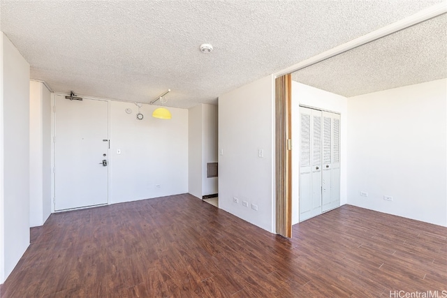 empty room featuring a textured ceiling and dark hardwood / wood-style floors