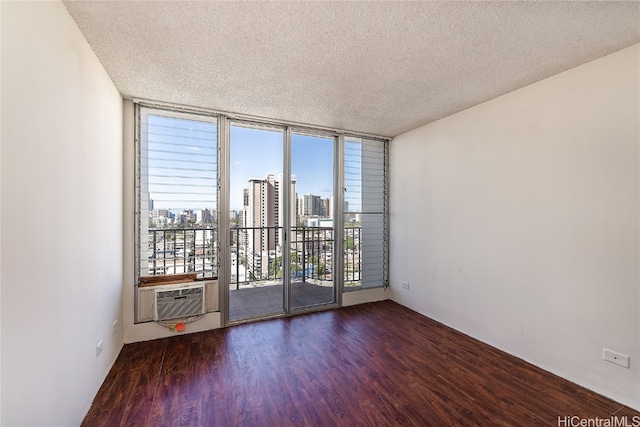 empty room featuring expansive windows, cooling unit, dark hardwood / wood-style floors, and a textured ceiling