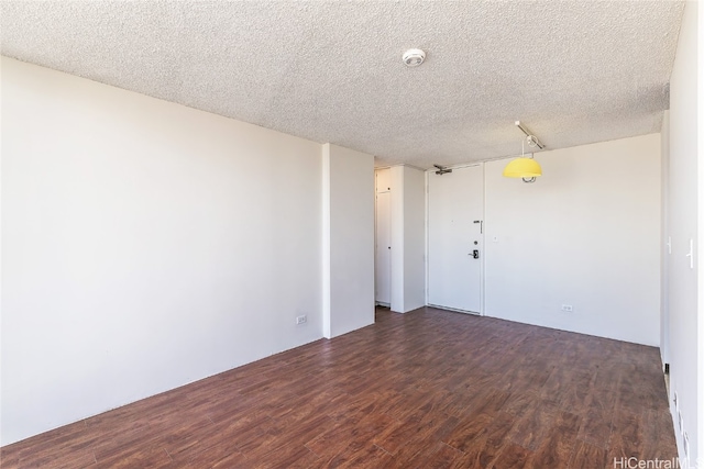 spare room featuring a textured ceiling and dark hardwood / wood-style flooring