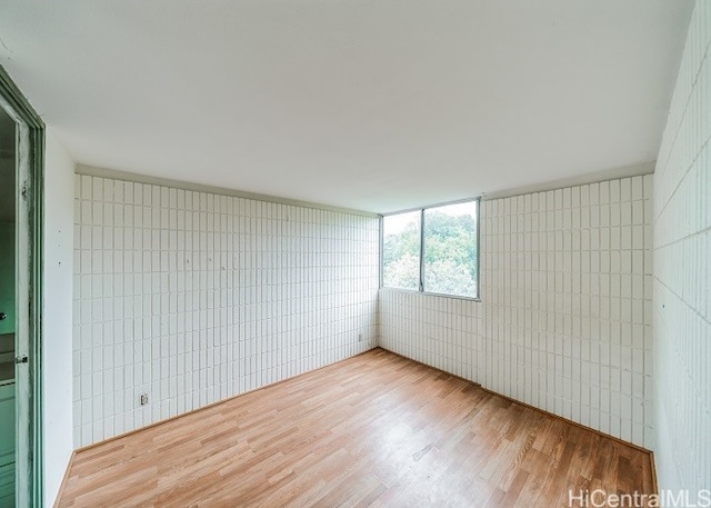 unfurnished room with tile walls and light wood-type flooring