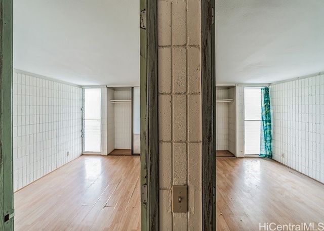 empty room featuring tile walls, light hardwood / wood-style flooring, and plenty of natural light