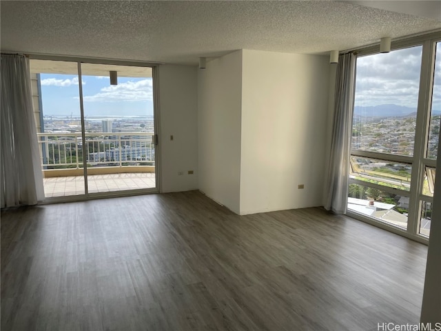 unfurnished room featuring a wall of windows, hardwood / wood-style flooring, and a healthy amount of sunlight