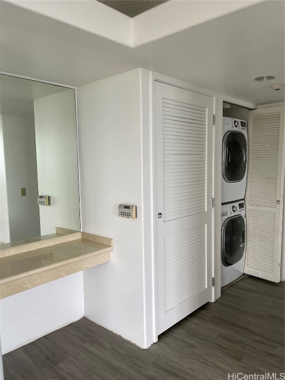 laundry room featuring stacked washing maching and dryer and dark hardwood / wood-style flooring