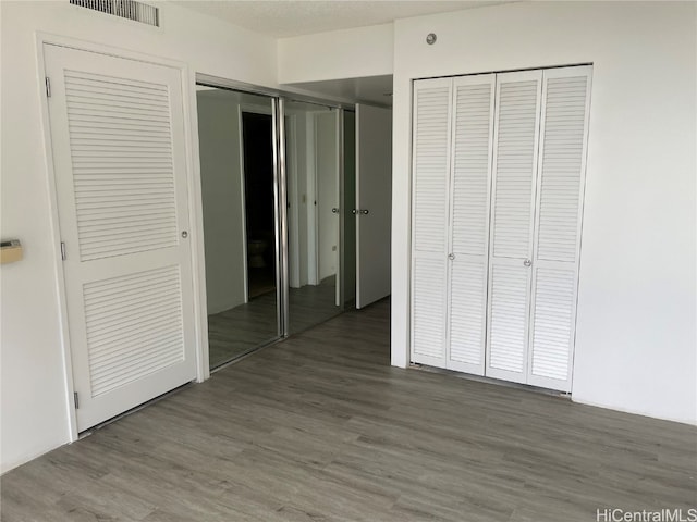 unfurnished bedroom featuring multiple closets, a textured ceiling, and dark hardwood / wood-style floors