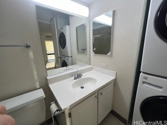 bathroom featuring vanity, stacked washer / dryer, and toilet