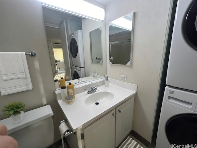 bathroom with vanity, stacked washer and dryer, and toilet